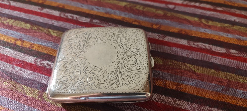 A square Victorian sterling silver cigarette case featuring hand-engraved foliate scrollwork and a blank central scalloped cartouche. View XVIII