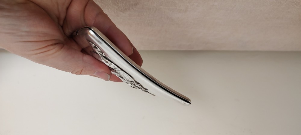 A rectangular silver Art Deco cigarette case featuring a detailed raised dragon motif across the front surface. View V