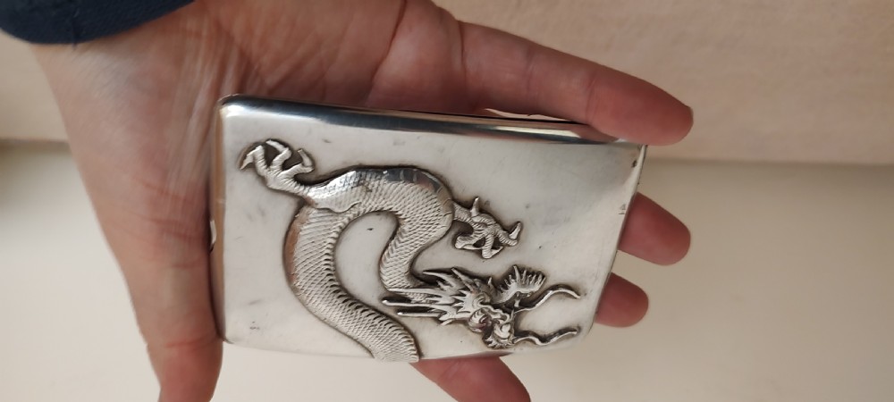 A rectangular silver Art Deco cigarette case featuring a detailed raised dragon motif across the front surface. View VIII
