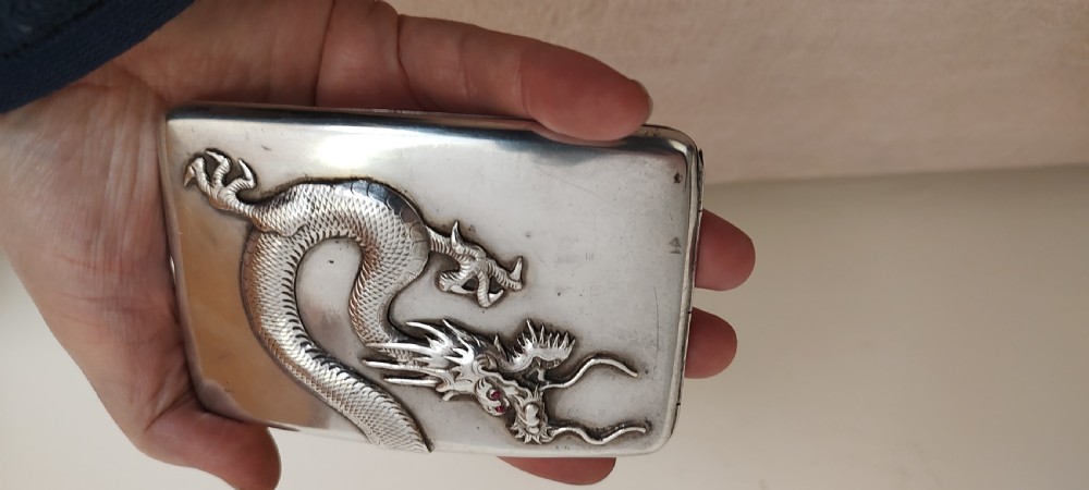 A rectangular silver Art Deco cigarette case featuring a detailed raised dragon motif across the front surface. View IX