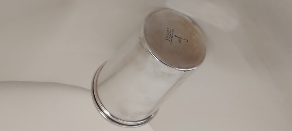 A polished silver-plated Art Deco three-piece cocktail shaker with ribbed collar details resting on a textured fabric surface. View IX