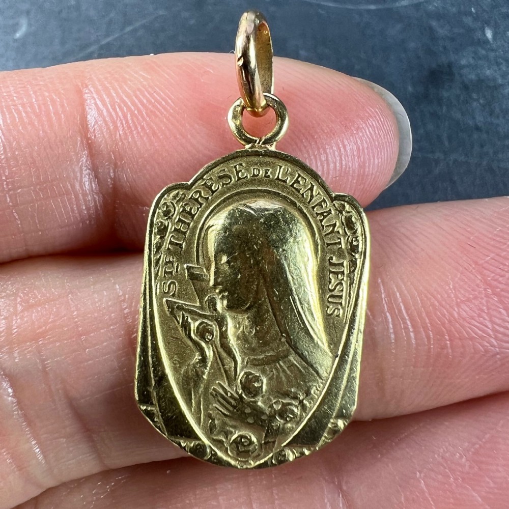 An oval 18ct yellow gold French pendant featuring a relief profile of Saint Therese holding a crucifix and roses. View IV