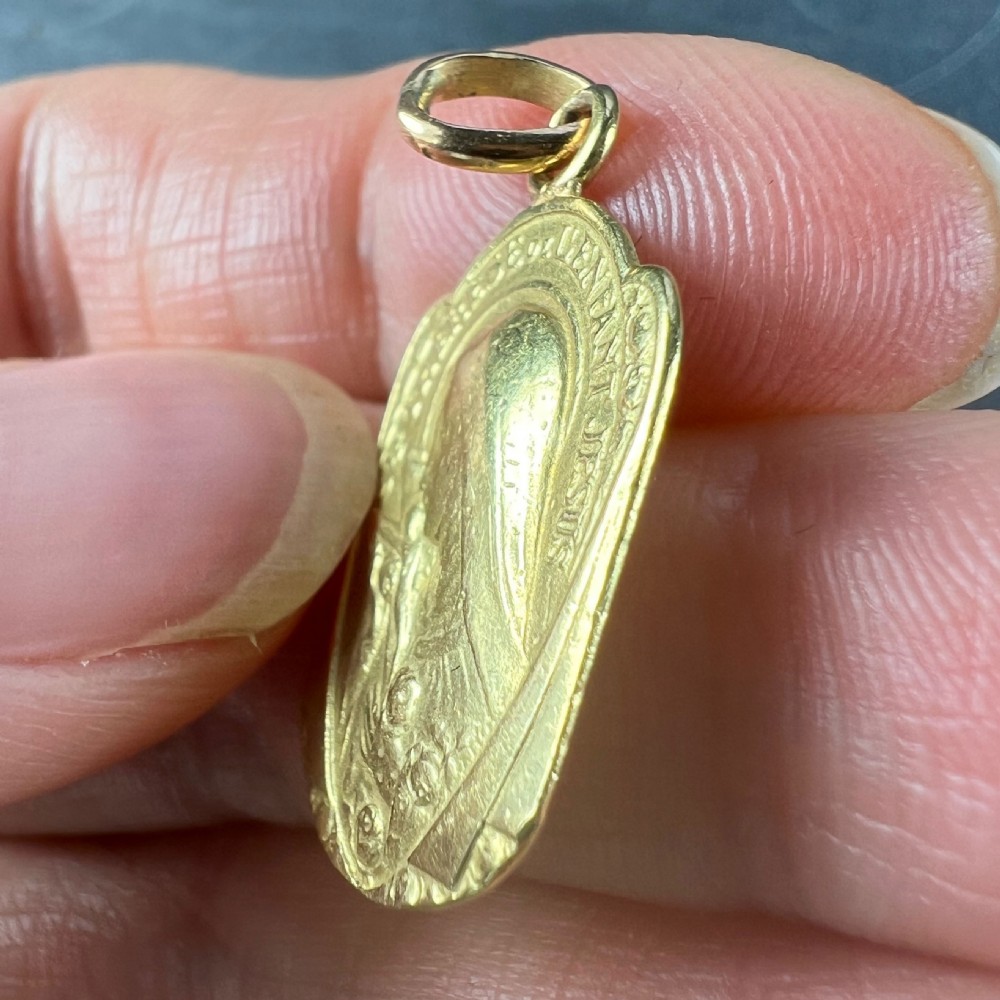 An oval 18ct yellow gold French pendant featuring a relief profile of Saint Therese holding a crucifix and roses. View VI