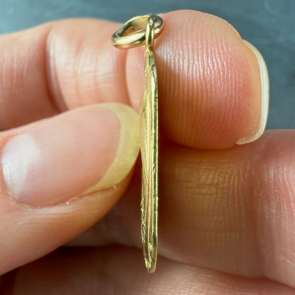 An oval 18ct yellow gold French pendant featuring a relief profile of Saint Therese holding a crucifix and roses. View VII