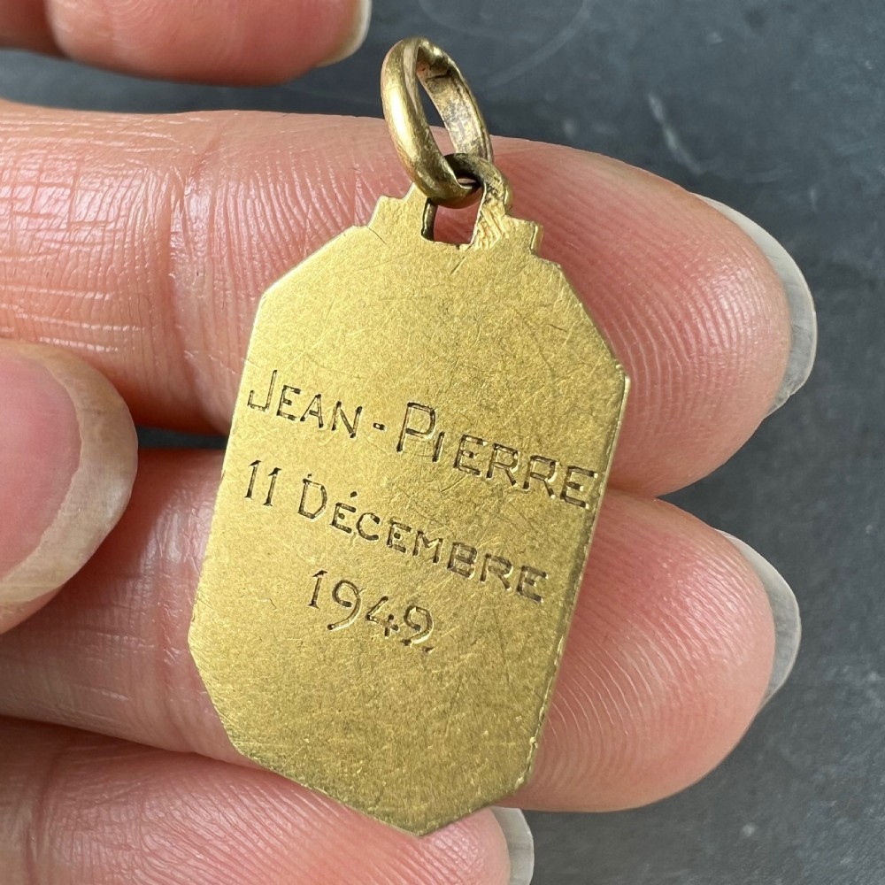 An octagonal 18k yellow gold pendant depicting Saint John the Baptist holding a cross, inscribed with ST JEAN. View IX