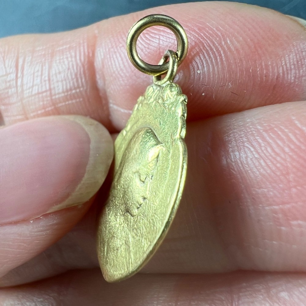An oval 18K yellow gold religious pendant featuring a relief profile of the Virgin Mary against a textured background with a top suspension loop. View V
