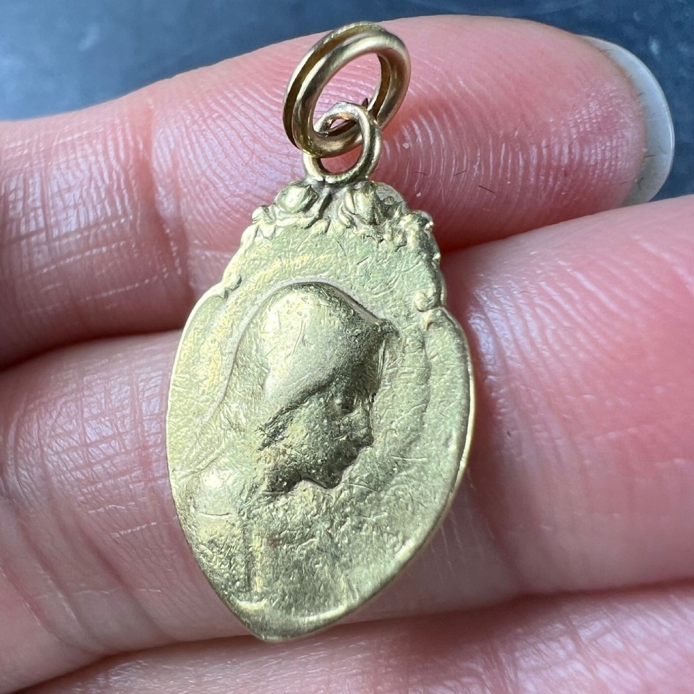 An oval 18K yellow gold religious pendant featuring a relief profile of the Virgin Mary against a textured background with a top suspension loop. View VII