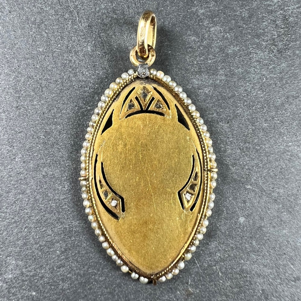 An oval 18ct yellow gold religious pendant depicting the Virgin Mary in profile, bordered by seed pearls and diamond accents. View IV