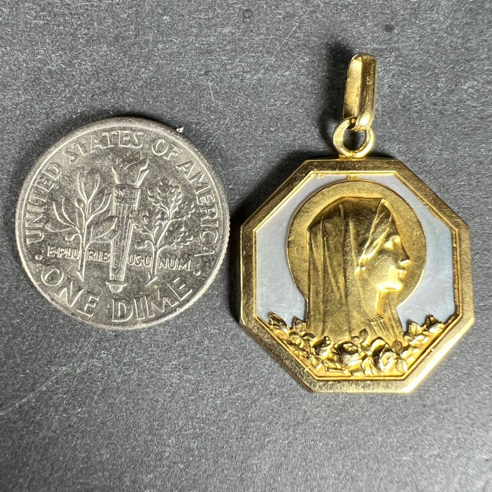 An octagonal 18K yellow gold pendant displaying a relief profile of the Virgin Mary set against a white mother-of-pearl background. View X