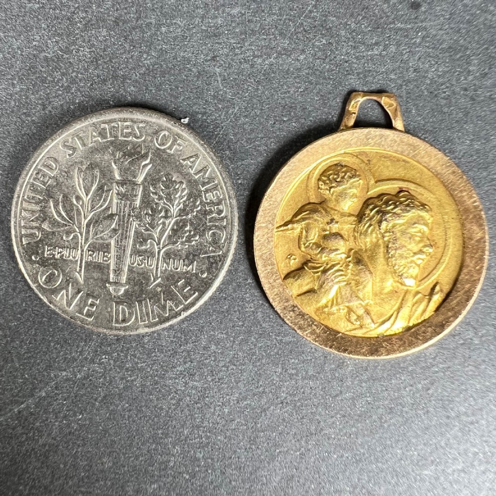 A circular 18K yellow gold Saint Christopher pendant featuring a bas-relief depiction of Saint Christopher carrying the Christ child, fitted with a suspension loop. View X