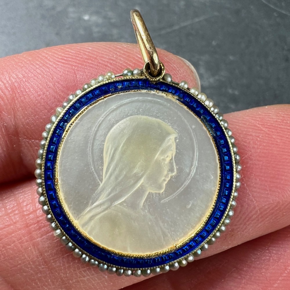 A circular 18K yellow gold pendant featuring a carved mother-of-pearl profile of the Virgin Mary, framed by a blue enamel ring and seed pearls. View V