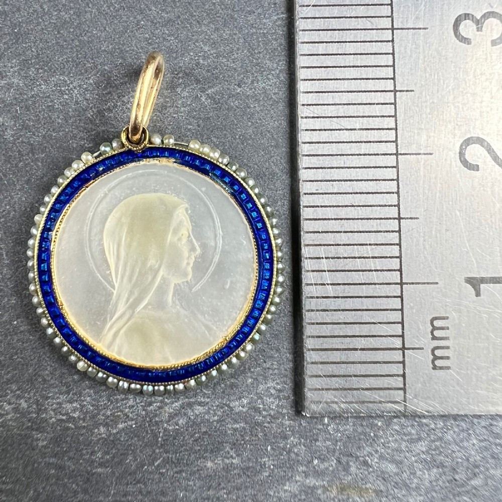 A circular 18K yellow gold pendant featuring a carved mother-of-pearl profile of the Virgin Mary, framed by a blue enamel ring and seed pearls. View IX