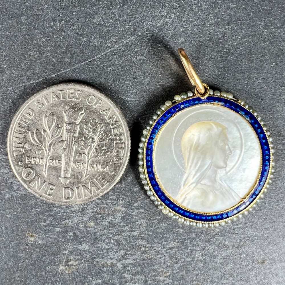 A circular 18K yellow gold pendant featuring a carved mother-of-pearl profile of the Virgin Mary, framed by a blue enamel ring and seed pearls. View X