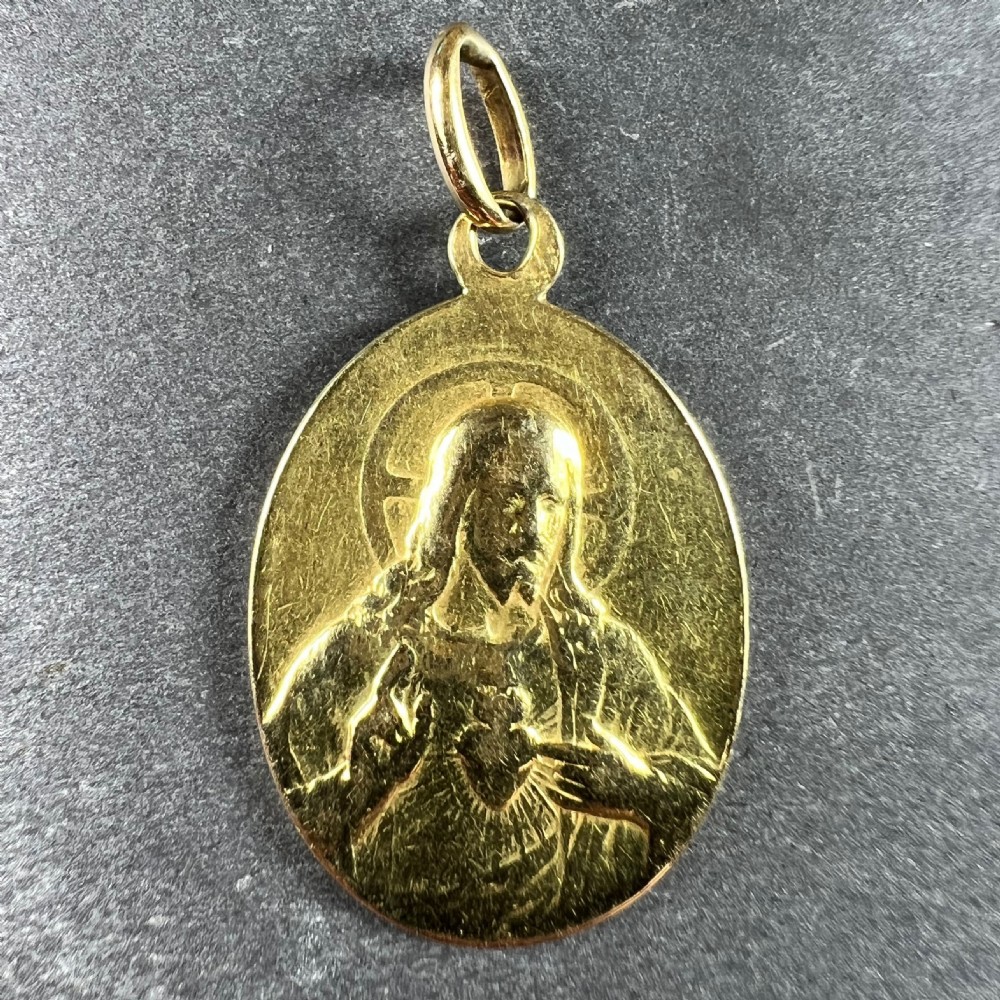An oval 18-carat yellow gold religious medal featuring a relief depiction of the Madonna and Child inscribed St Scapulaire. View III