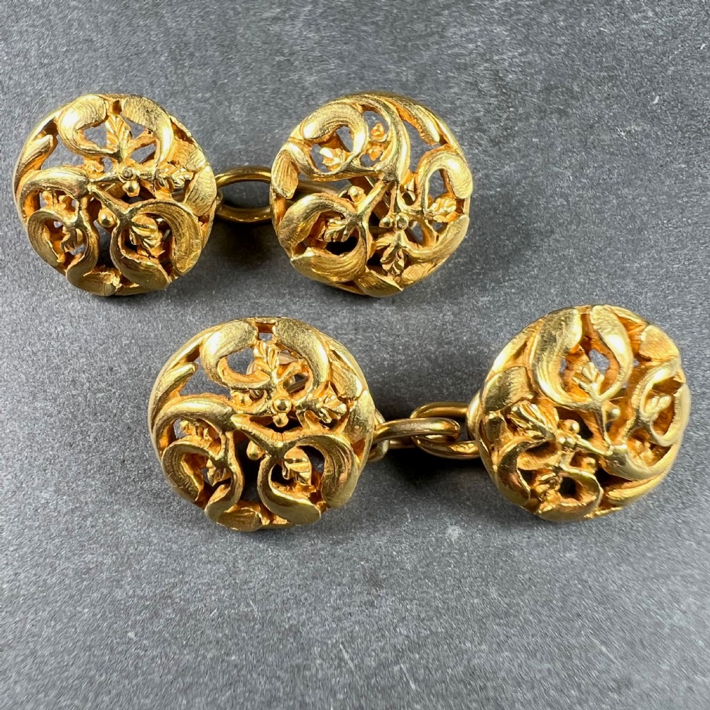 A pair of circular 18-carat yellow gold Art Nouveau cufflinks featuring pierced openwork mistletoe leaf motifs connected by chain links. View II
