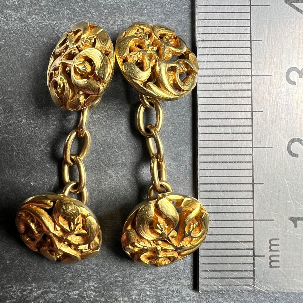 A pair of circular 18-carat yellow gold Art Nouveau cufflinks featuring pierced openwork mistletoe leaf motifs connected by chain links. View XII