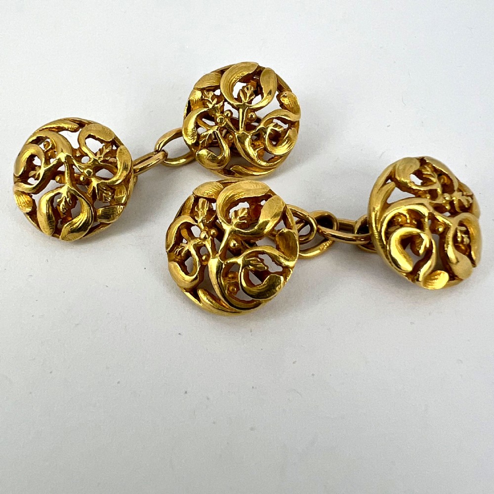 A pair of circular 18-carat yellow gold Art Nouveau cufflinks featuring pierced openwork mistletoe leaf motifs connected by chain links. View XIV