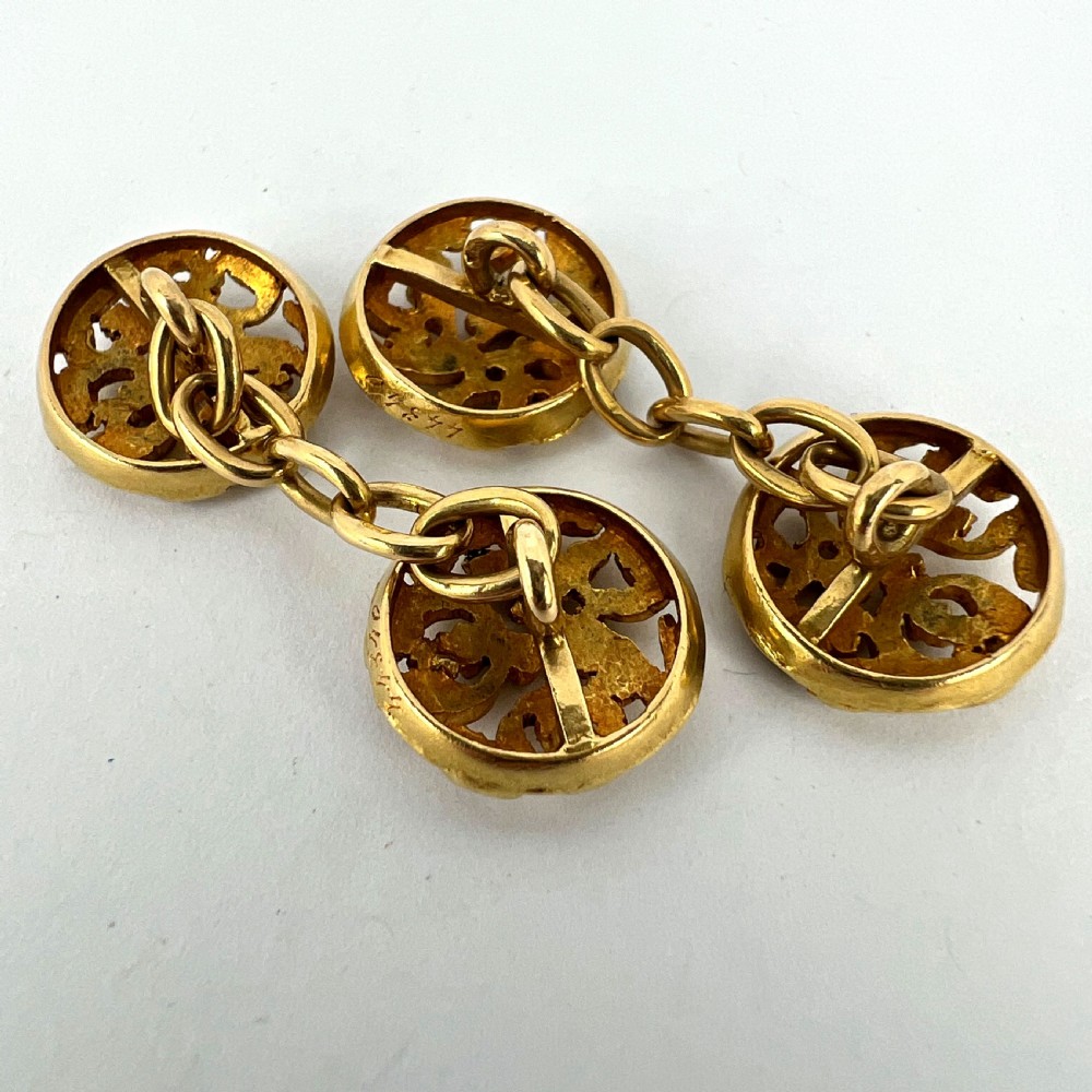 A pair of circular 18-carat yellow gold Art Nouveau cufflinks featuring pierced openwork mistletoe leaf motifs connected by chain links. View XVI