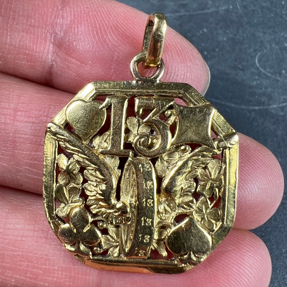An octagonal 18ct yellow gold openwork charm pendant featuring the number 13, playing card suits, a wheel, and four-leaf clovers. View V