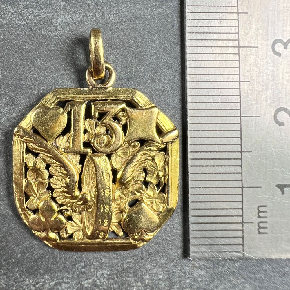 An octagonal 18ct yellow gold openwork charm pendant featuring the number 13, playing card suits, a wheel, and four-leaf clovers. View IX