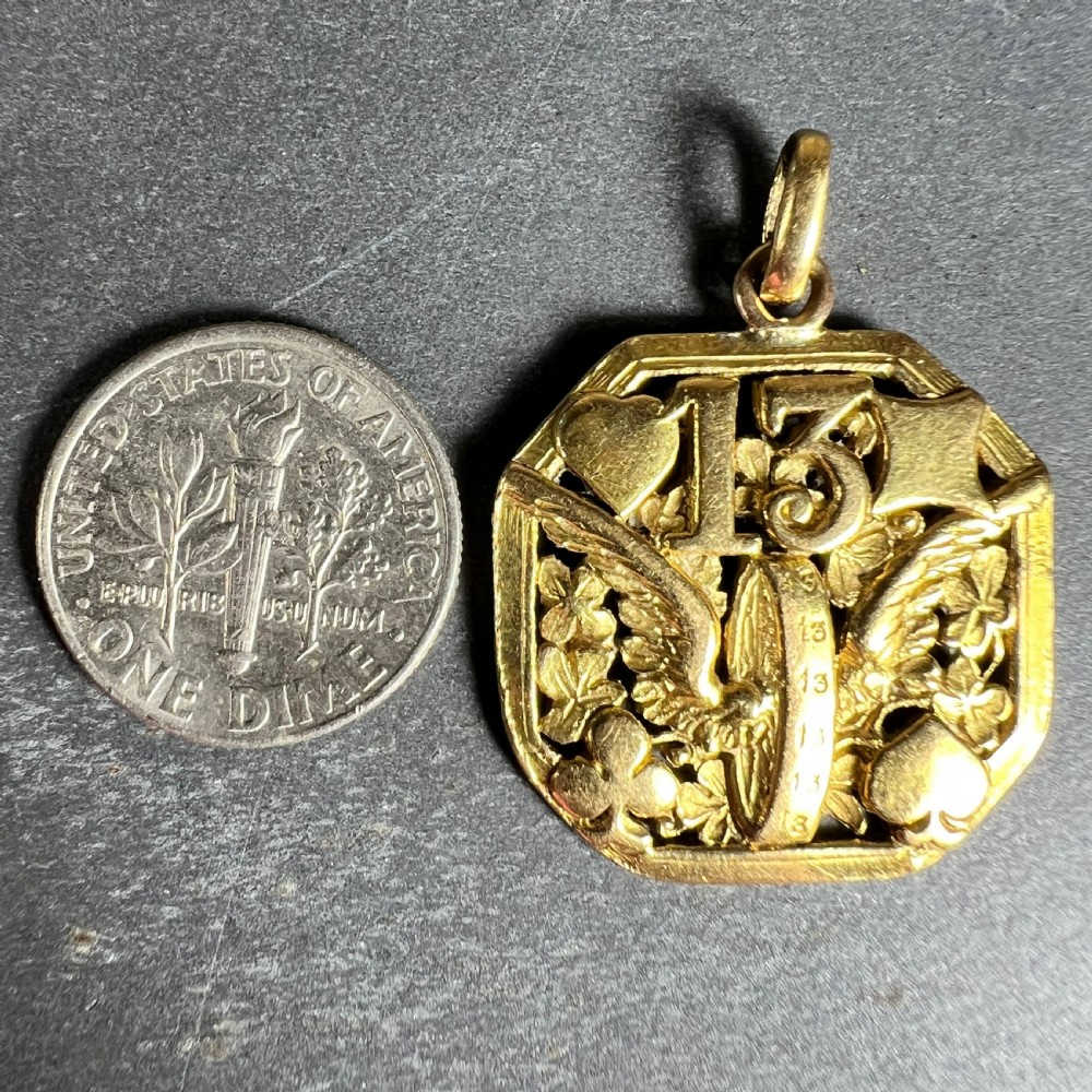 An octagonal 18ct yellow gold openwork charm pendant featuring the number 13, playing card suits, a wheel, and four-leaf clovers. View X