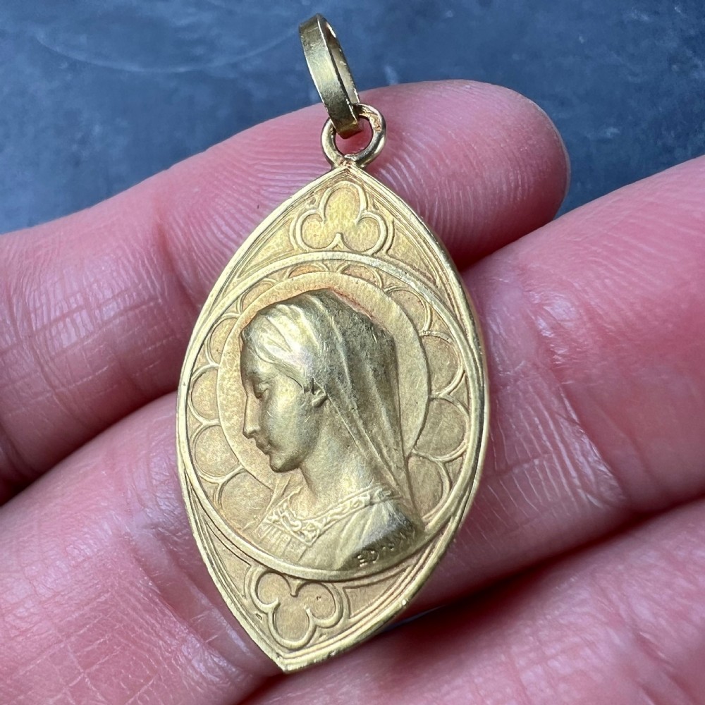 An almond-shaped 18K yellow gold pendant depicting a profile relief of the Virgin Mary surrounded by Gothic arch details. View V