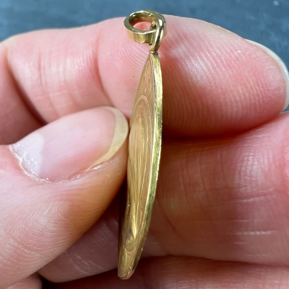 An almond-shaped 18K yellow gold pendant depicting a profile relief of the Virgin Mary surrounded by Gothic arch details. View IX