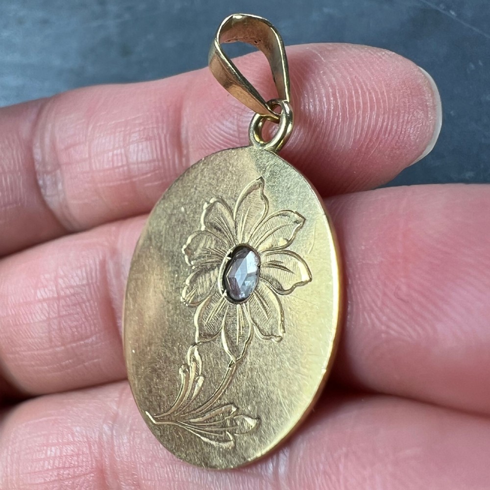 A circular 18 karat yellow gold pendant featuring an engraved daisy flower motif with a centrally set diamond and a top hanging bail. View VIII