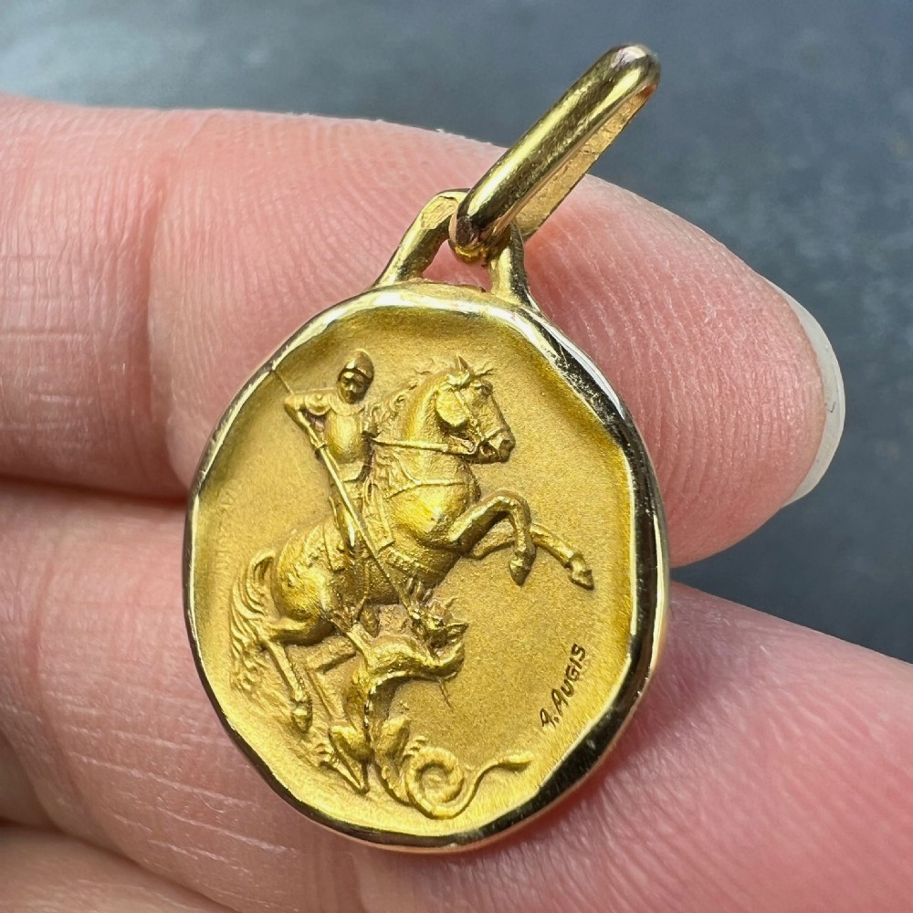 An antique circular 18-carat yellow gold charm pendant depicting Saint George slaying a dragon in high relief. View VI