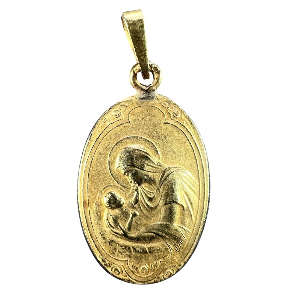 An oval 18ct yellow gold Art Nouveau medal pendant featuring a raised relief depiction of the Madonna holding the Christ Child.