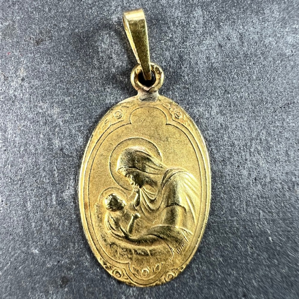 An oval 18ct yellow gold Art Nouveau medal pendant featuring a raised relief depiction of the Madonna holding the Christ Child. View II