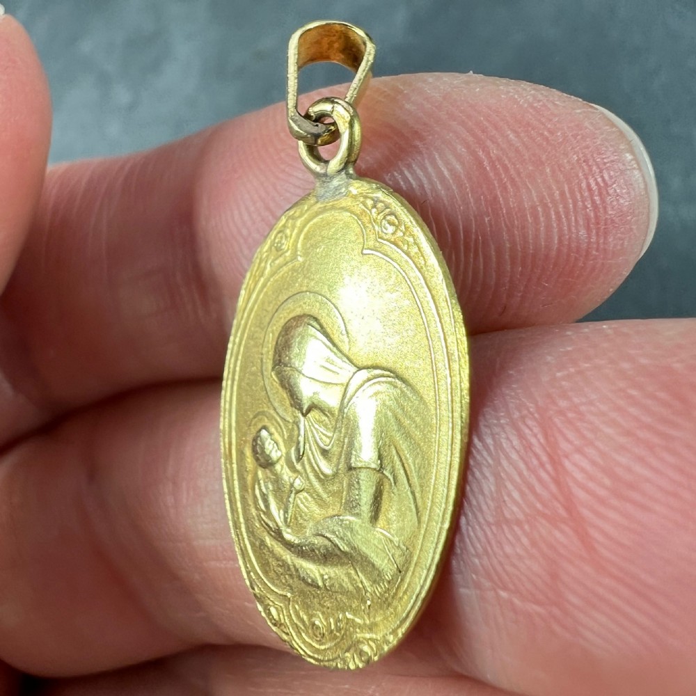 An oval 18ct yellow gold Art Nouveau medal pendant featuring a raised relief depiction of the Madonna holding the Christ Child. View VII