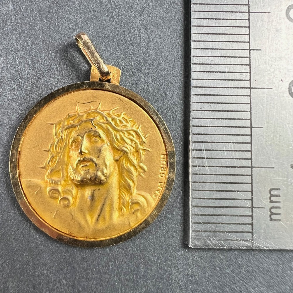 A circular 18ct yellow gold religious medal featuring a relief depiction of Jesus Christ wearing a crown of thorns. View X