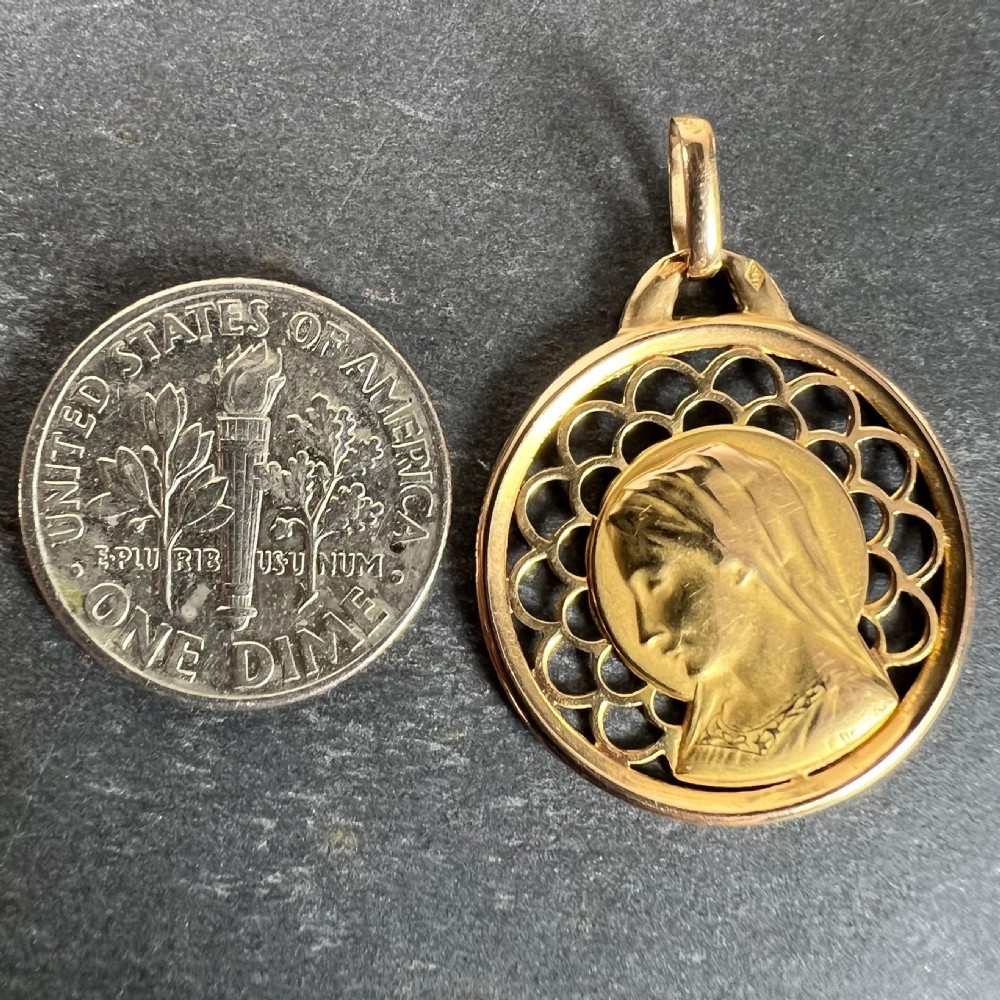 A circular 18-carat yellow gold medal pendant featuring a profile relief of the Virgin Mary surrounded by a pierced scalloped lattice border. View X