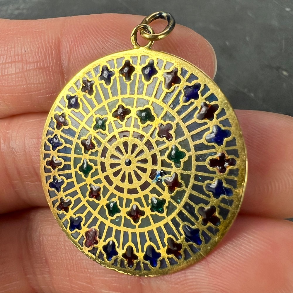 A circular 18k yellow gold pendant featuring translucent plique-a-jour enamelling in a geometric cathedral rose window motif. View X