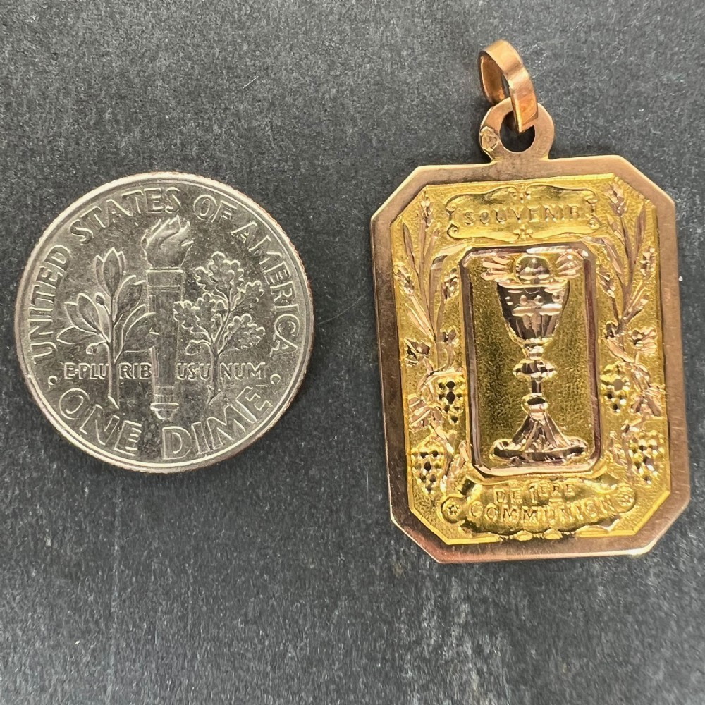An octagonal multi-tone 18ct gold religious pendant displaying an embossed chalice relief surrounded by French communion text and wheat motifs. View XI