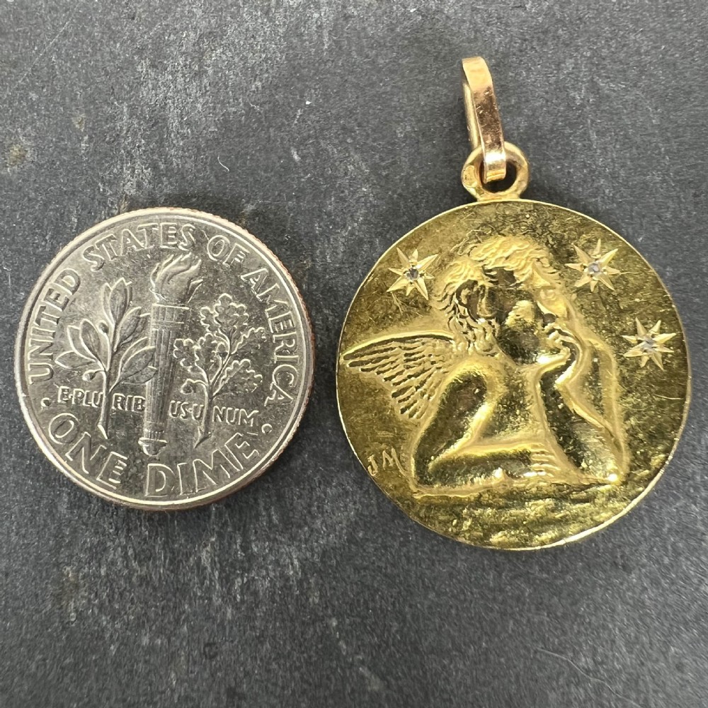 A circular 18k yellow gold medallion pendant featuring a relief motif of Raphaels cherub accented by star-set diamonds. View XI