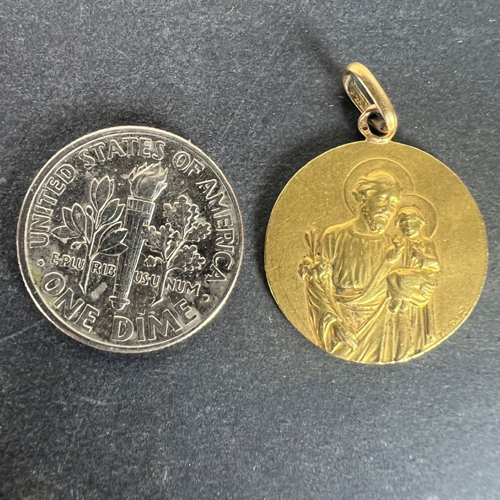 A circular 18K yellow gold medal pendant featuring a bas-relief carving of Saint Joseph holding the Christ Child, signed Tairac at the bottom. View XI