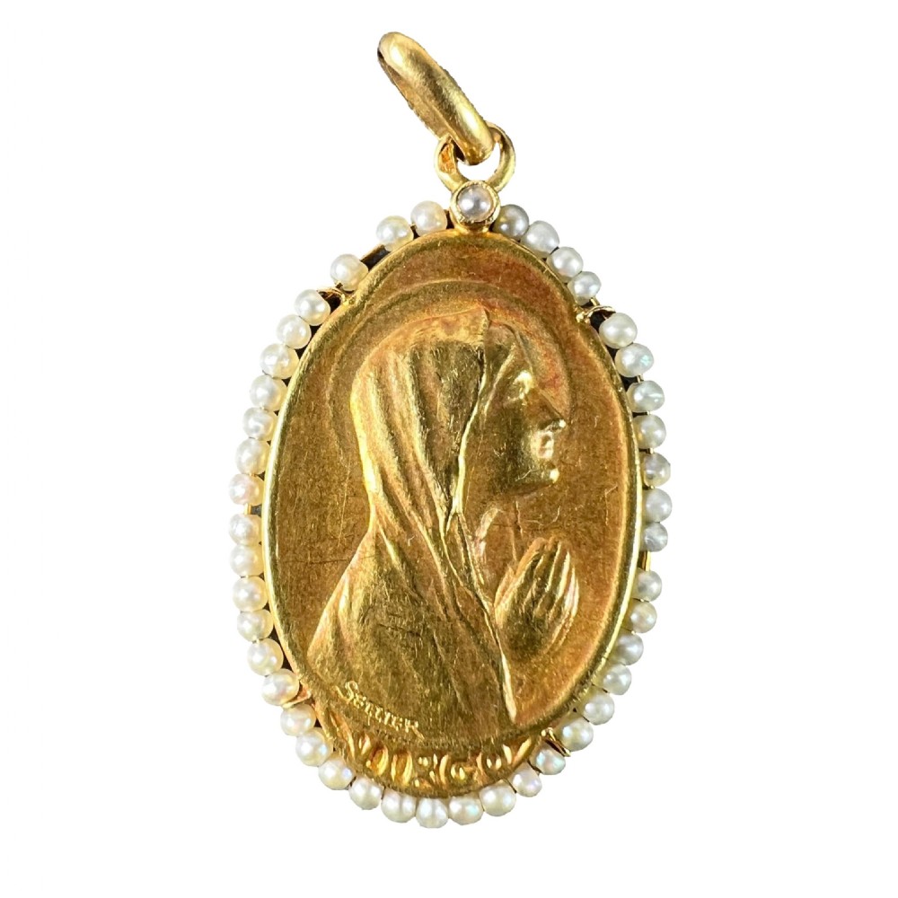 An oval 18ct yellow gold religious pendant depicting the Virgin Mary in profile, bordered by small seed pearls.
