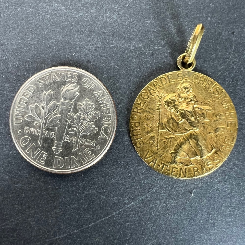 An oval 18-carat yellow gold religious medal depicting Saint Christopher carrying the Christ Child with a French text border inscription. View X