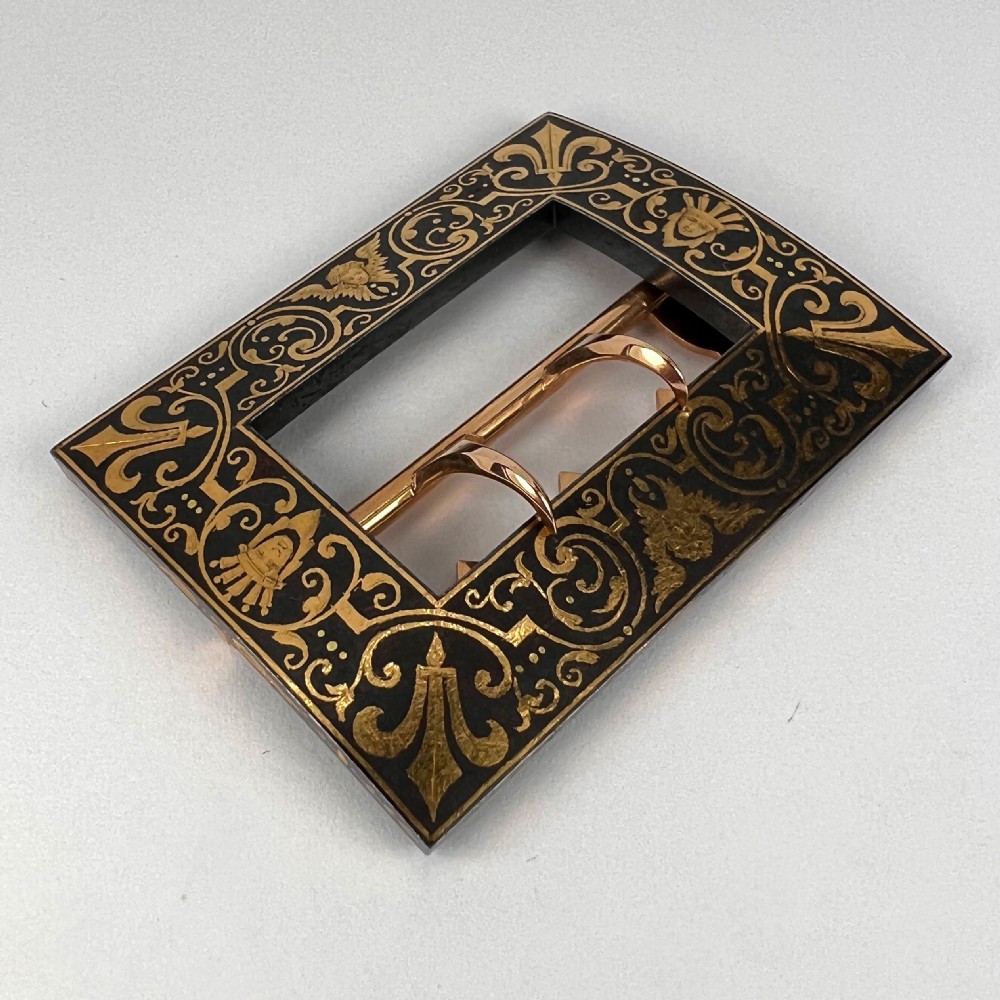 A rectangular damascene steel belt buckle decorated with gold inlaid scrollwork, cherub faces, and a double-prong central mechanism. View XVI
