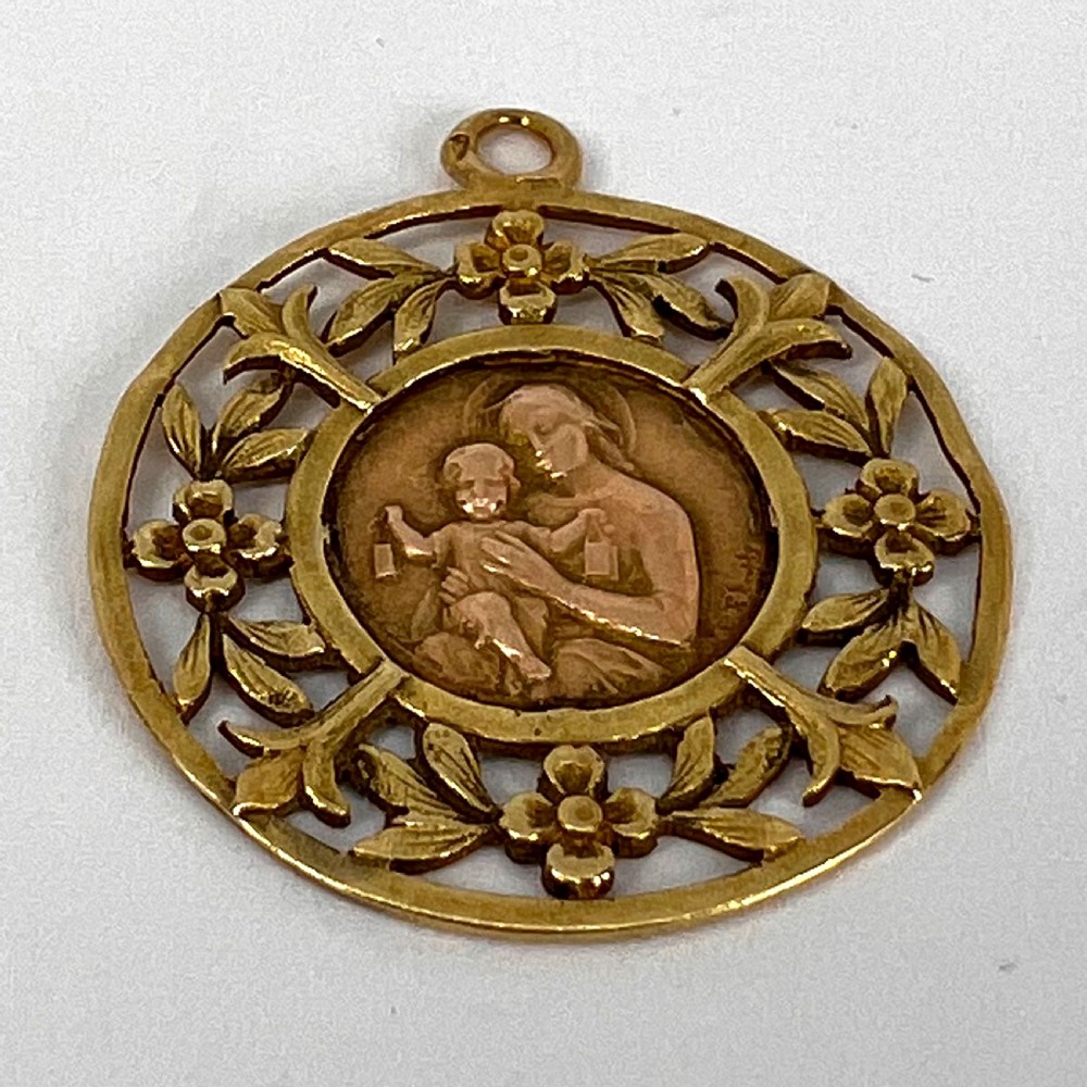 A circular 18-carat yellow gold religious pendant depicting the Madonna and Child in relief surrounded by an intricate openwork floral border. View XI