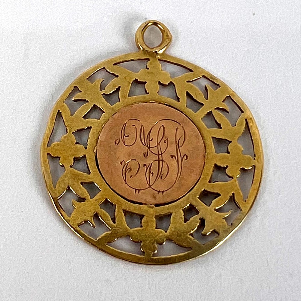 A circular 18-carat yellow gold religious pendant depicting the Madonna and Child in relief surrounded by an intricate openwork floral border. View XIII