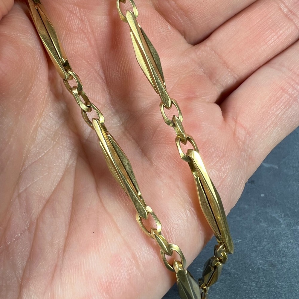 An antique 18ct yellow gold French watch chain composed of faceted elongated links and small connecting rings with a swivel clasp. View XII