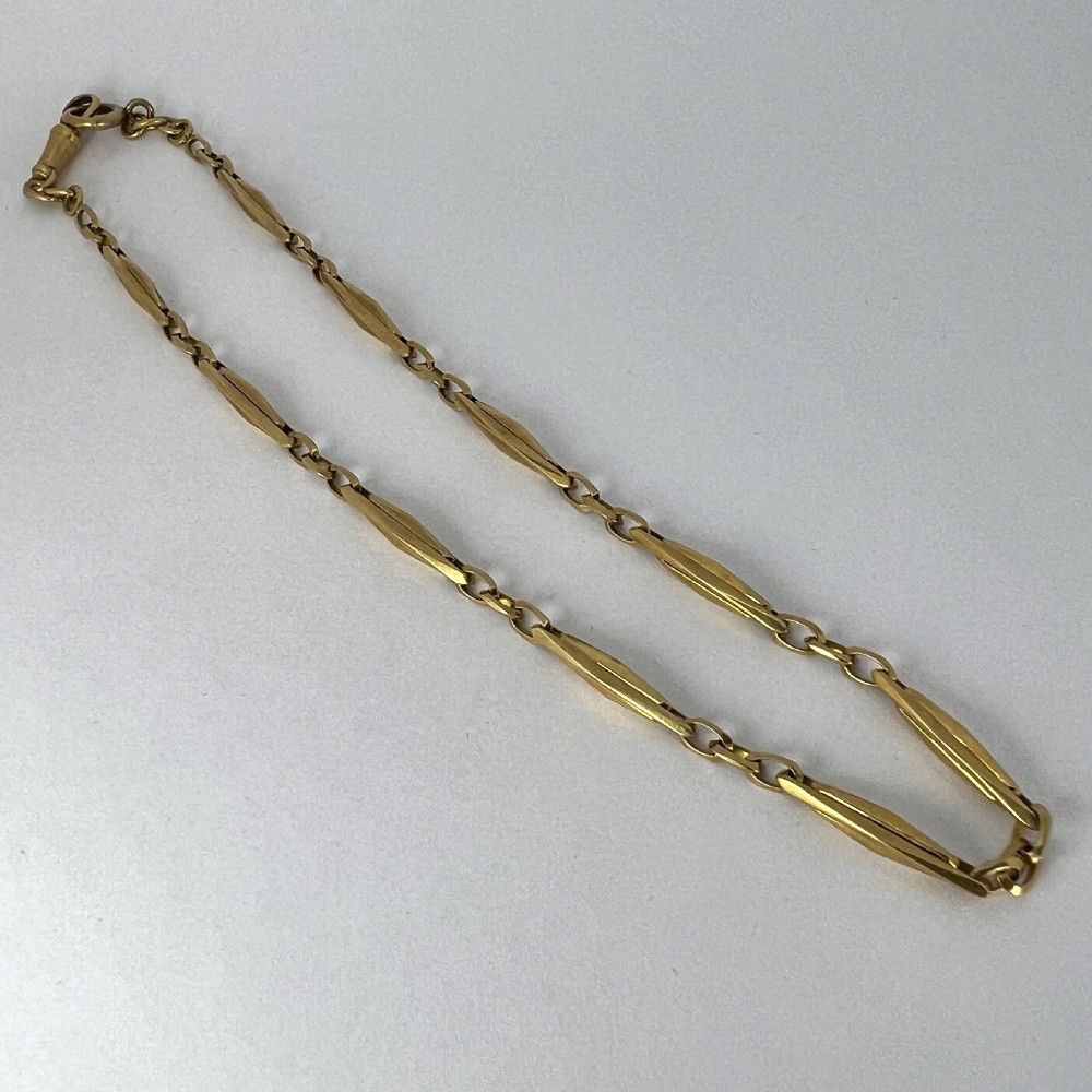 An antique 18ct yellow gold French watch chain composed of faceted elongated links and small connecting rings with a swivel clasp. View XV