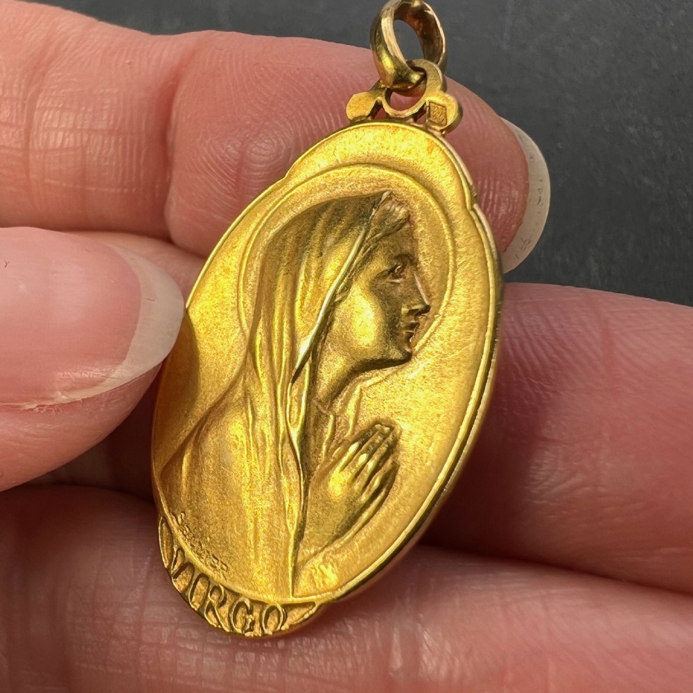 An oval 18k yellow gold religious medal depicting a profile bas-relief of the Virgin Mary in prayer with the inscription Virgo and signature Sellier. View VII