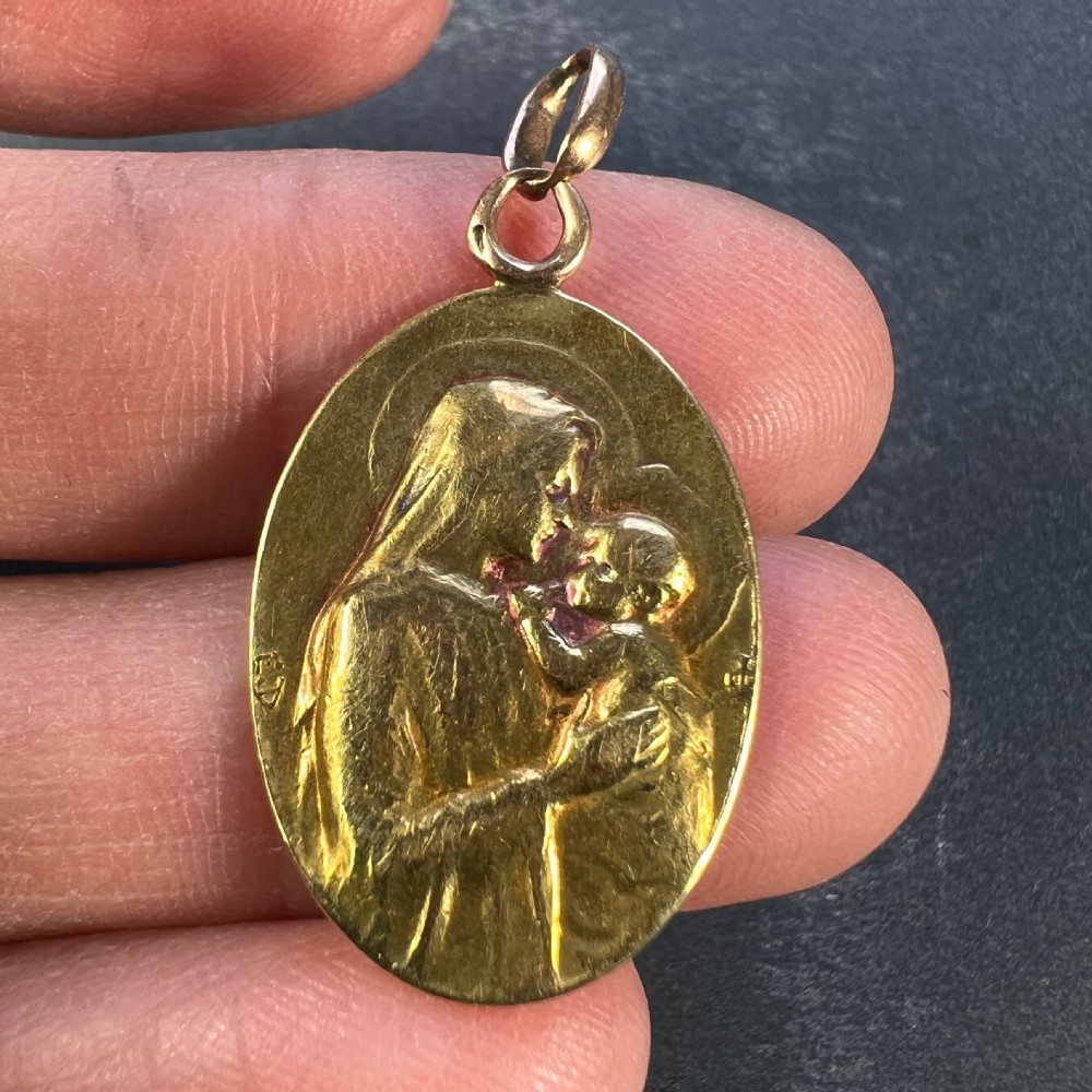 An oval 18ct yellow gold devotional pendant featuring a relief carving of the Madonna and Child. View V