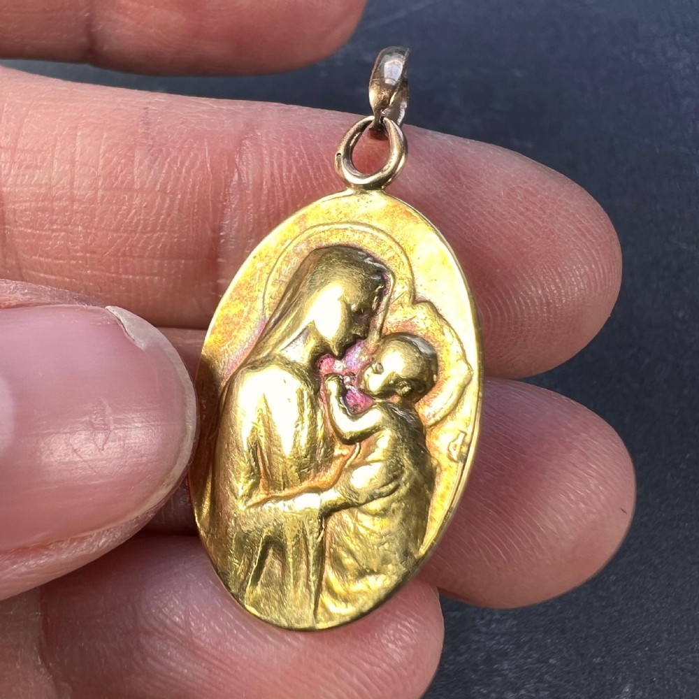 An oval 18ct yellow gold devotional pendant featuring a relief carving of the Madonna and Child. View VI