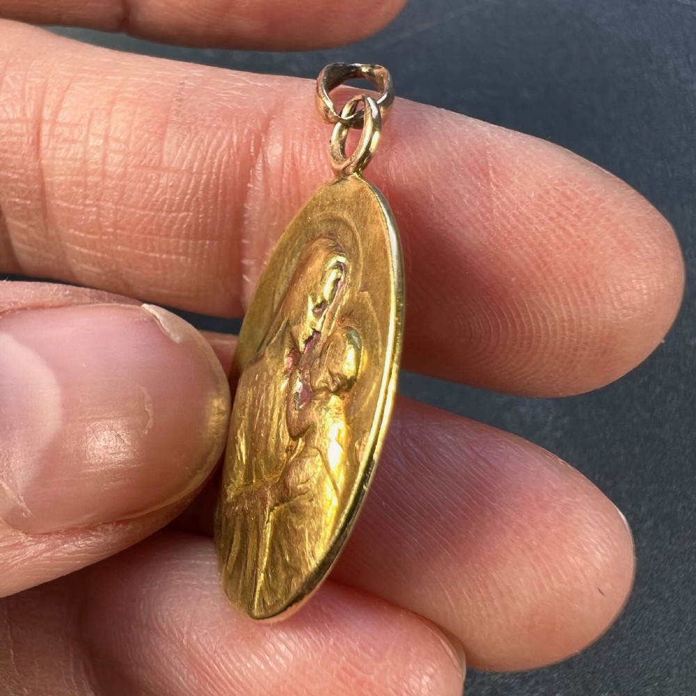 An oval 18ct yellow gold devotional pendant featuring a relief carving of the Madonna and Child. View VII