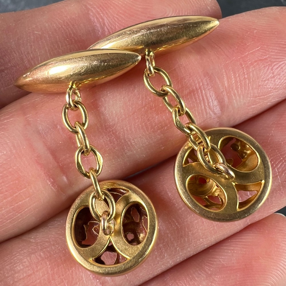 A pair of circular 18ct yellow gold Art Nouveau cufflinks featuring pierced mistletoe foliage linked by chain to torpedo-shaped backs. View IX